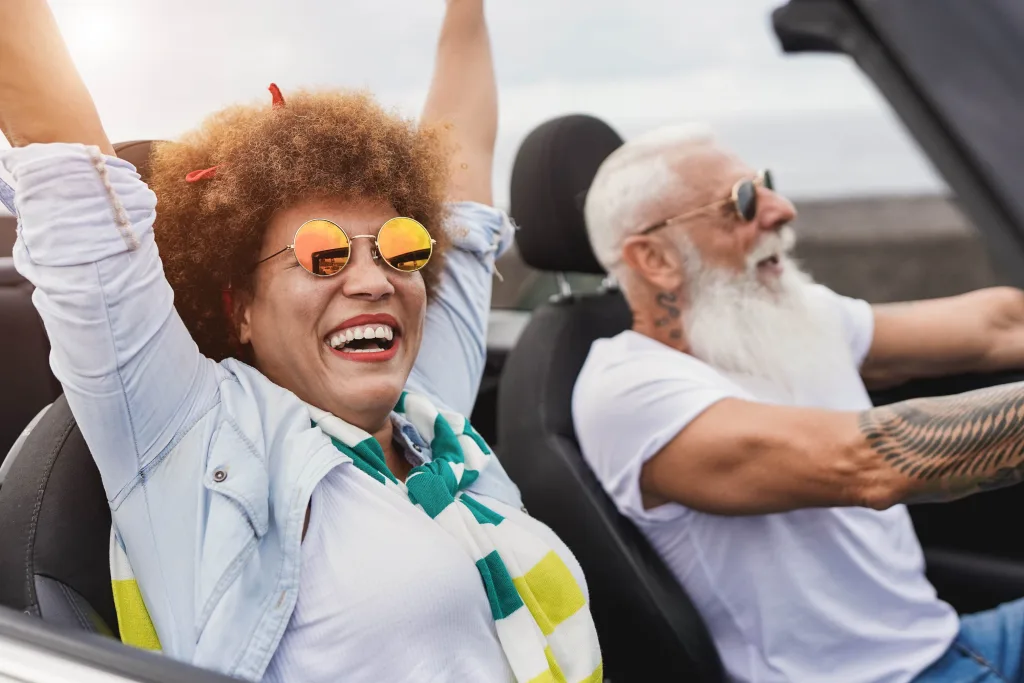 Trendy senior couple having fun inside convertible car